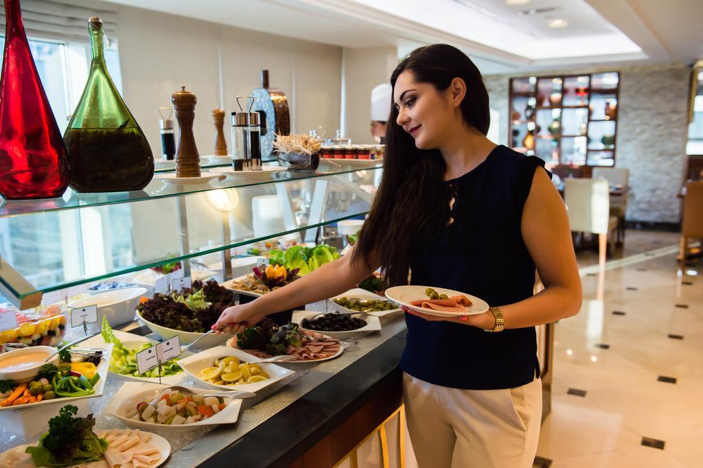 Grand Mercure Majlis Residences Abú Dhabí Exteriér fotografie A woman selecting food from a buffet